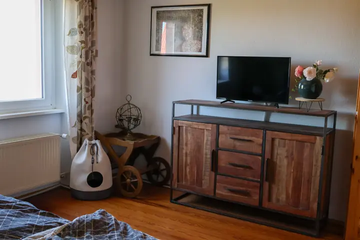 Ground floor bedroom with wooden floorboards and sideboard